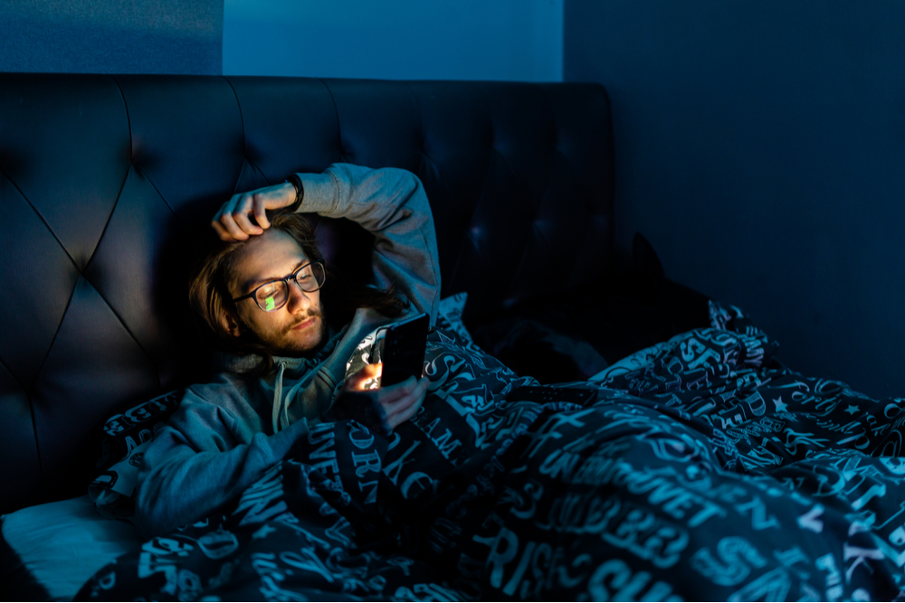 Man in bed late at night, wondering how social media affects us negatively