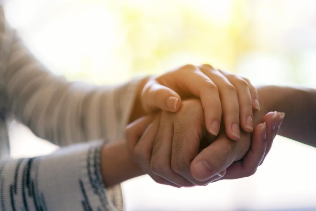 a woman holds the hand of a loved one as they discuss finding addiction help for your partner in texas