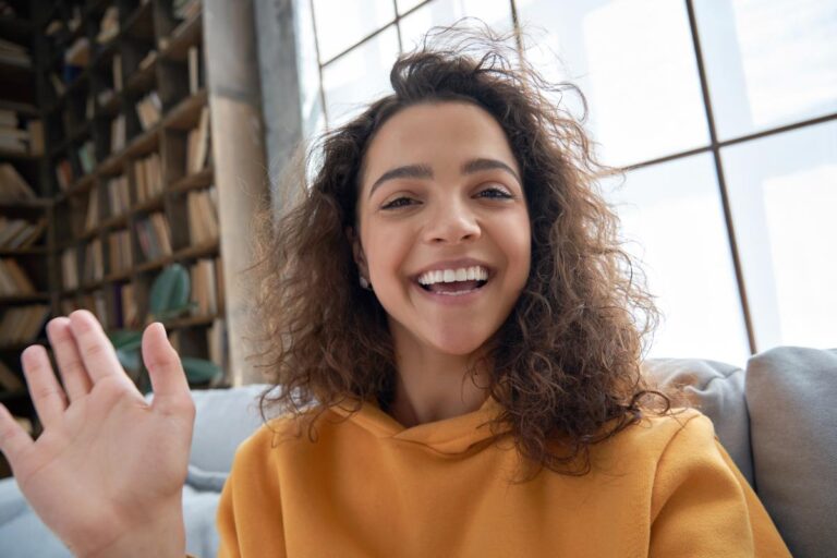 a woman waves to participants at a virtual addiction treatment program