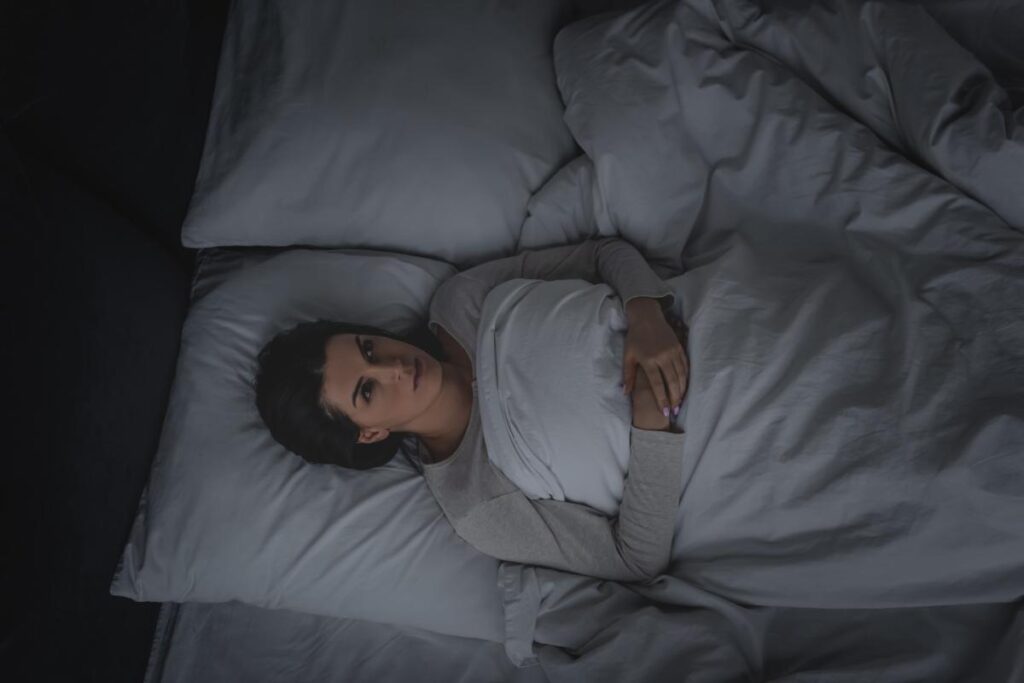 Person in bed, experiencing nightmares and alcohol abuse symptoms