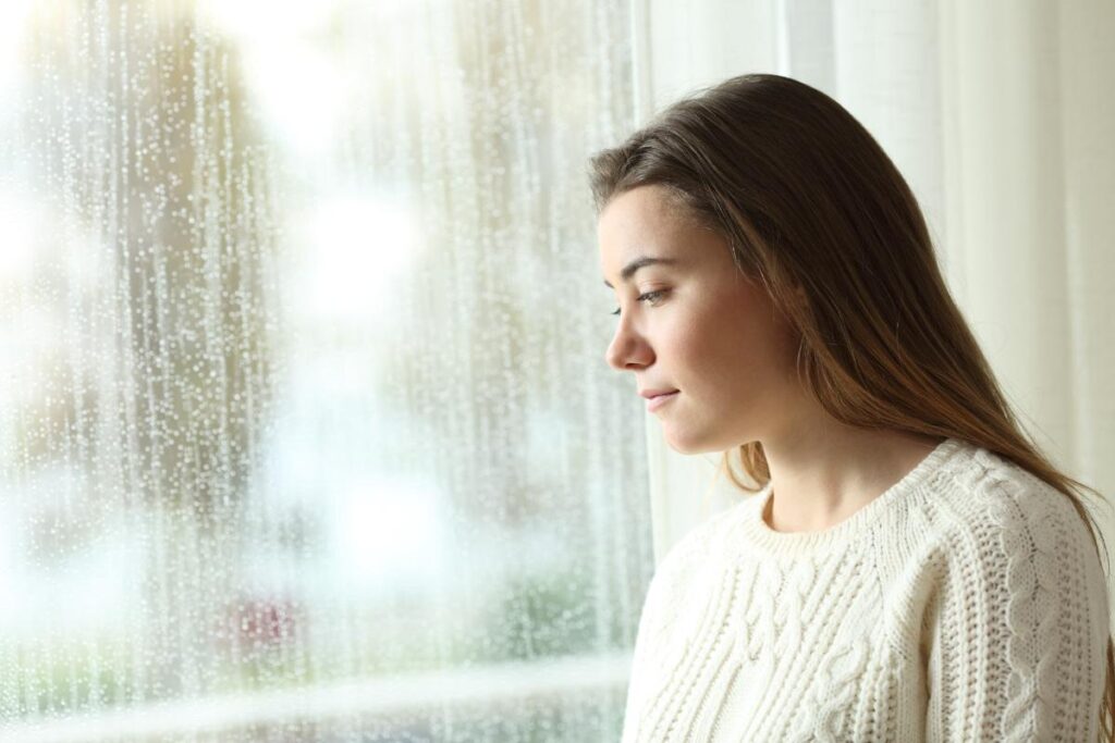 Person looking out a window and thinking of the dangers of using opioids during winter