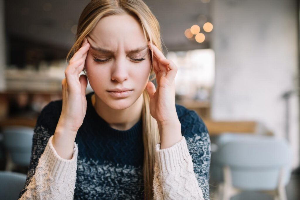 Person with a headache after finding out what the signs of prescription pill addiction are